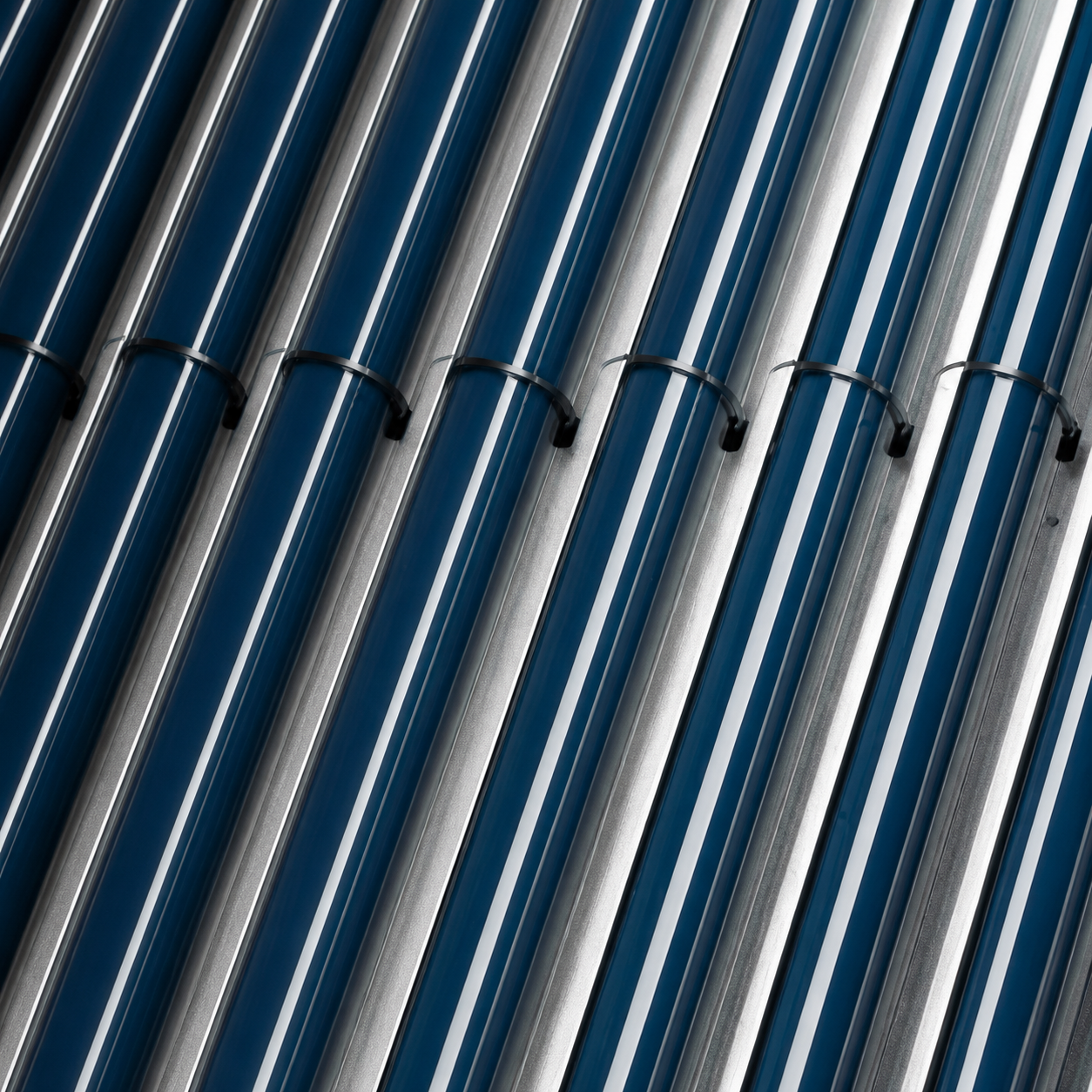 05A44F5C-0CB7-476D-9CD9-AC71166B27FE - Pleion Close-up of diagonal blue and silver metallic tubes bound by black ties, creating a repeating pattern.