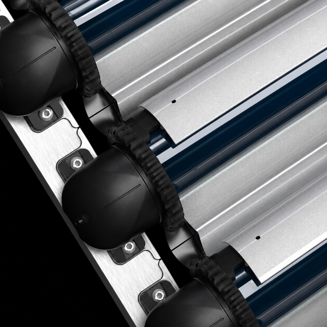 79DD7E88-2C75-4249-A9AA-CB6A979137F0 - Pleion Close-up of an industrial roller conveyor showing black drive wheels and silver metal rollers on a dark background.