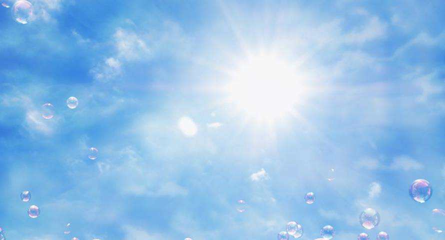 Bright blue sky with a radiant sun and floating soap bubbles catching the light.