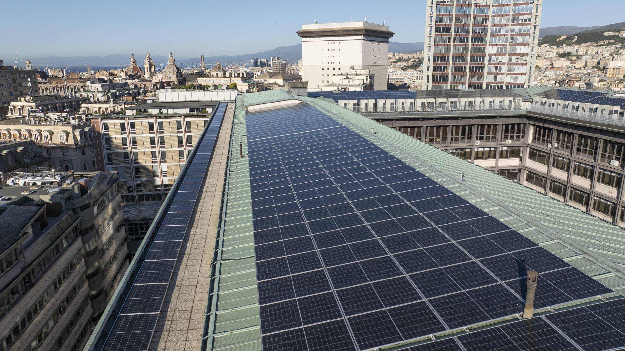 default - Pleion Rooftop covered in dark solar panels overlooking a dense city with domed towers and distant hills/ocean.